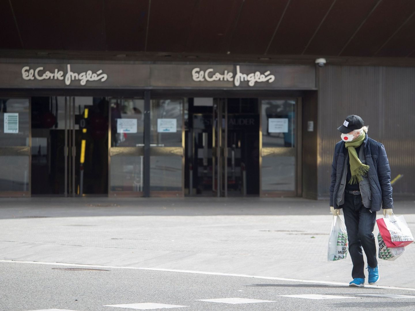 Una mujer con mascarilla camina ante un establecimiento de El Corte Inglés. (EFE)