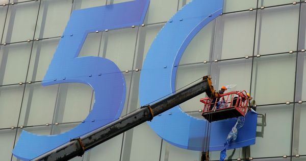 Foto: Varios operarios colocan el logo del 5G en un edificio. (Reuters)