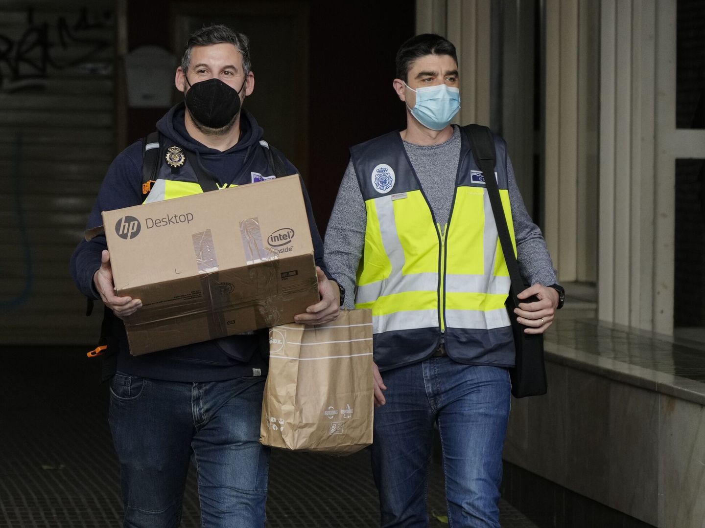 Agentes de la Policía Nacional portan material incautado del área de Cultura y Deportes del Ayuntamiento de Cornellà de Llobregat. (EFE/Enric Fontcuberta)