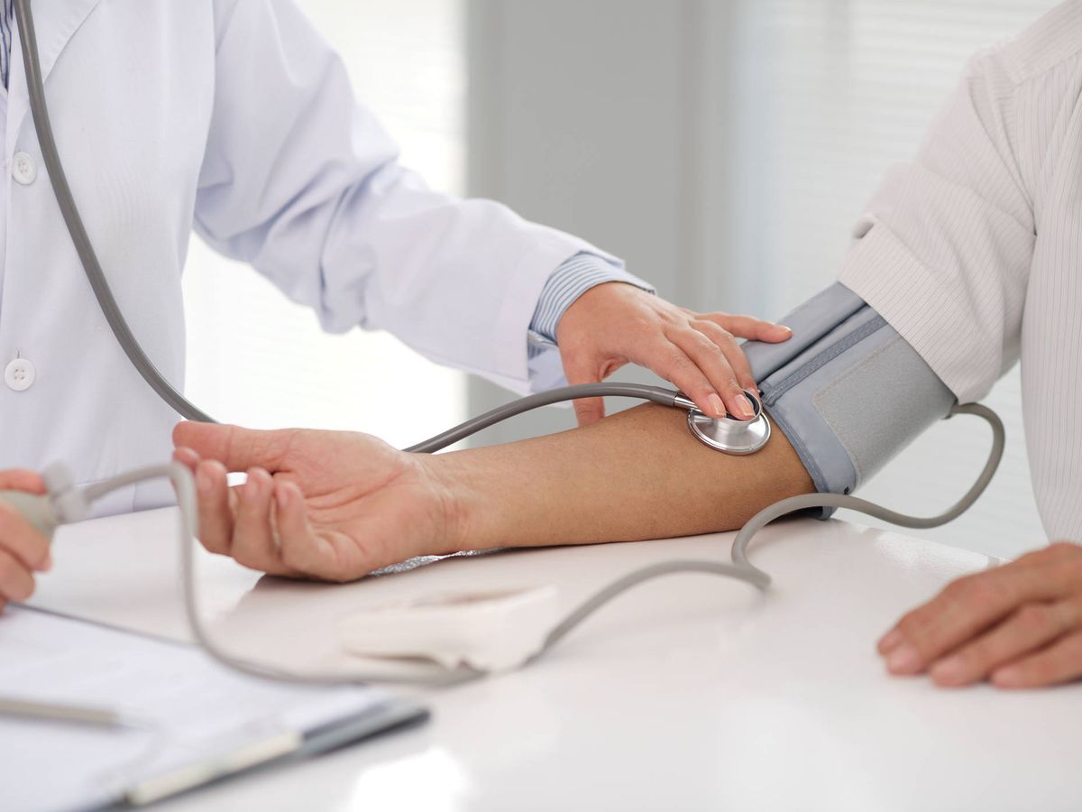 Foto: Un médico mide la tensión a un paciente para comprobar si tiene la presión arterial alta. (iStock)