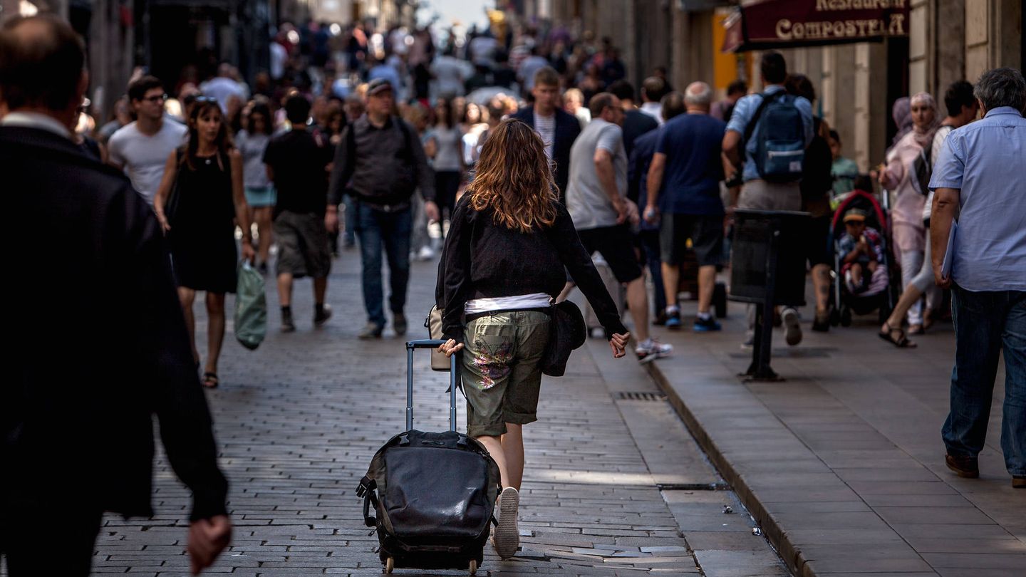Una turista camina con una maleta por las calles de Barcelona. (EFE)