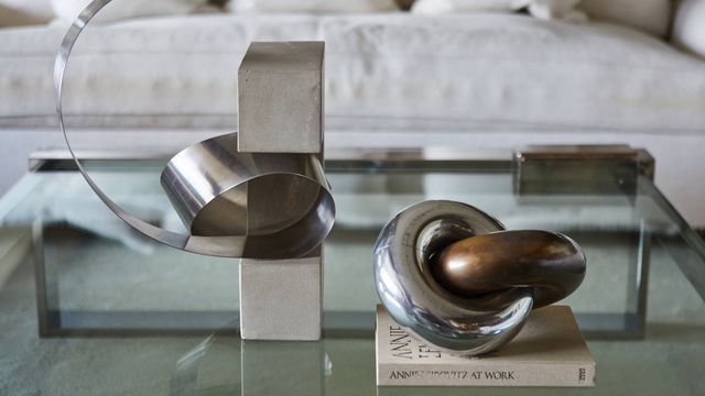 Dos esculturas metálicas geométricas pequeñas centran el protagonismo de la mesa de centro de la sala de estar. 