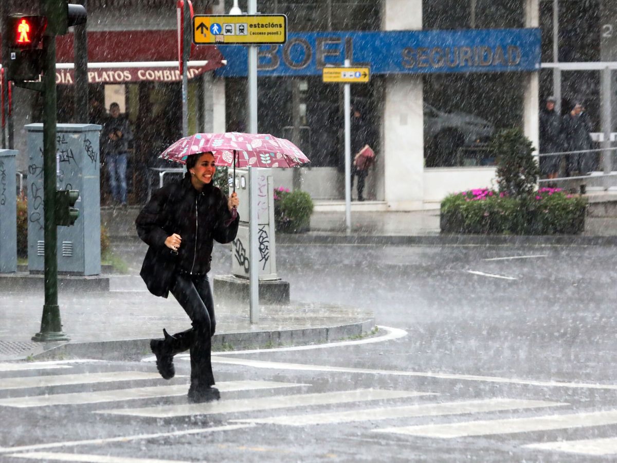 Foto: Una mujer camina bajo la lluvia en Santiago de Compostela. (EFE/Xoán Rey)