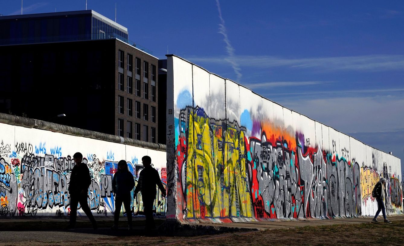 Varias personas caminan junto a la East Side Gallery, el más largo tramo que queda en pie del muro, en Berlín. (EFE)