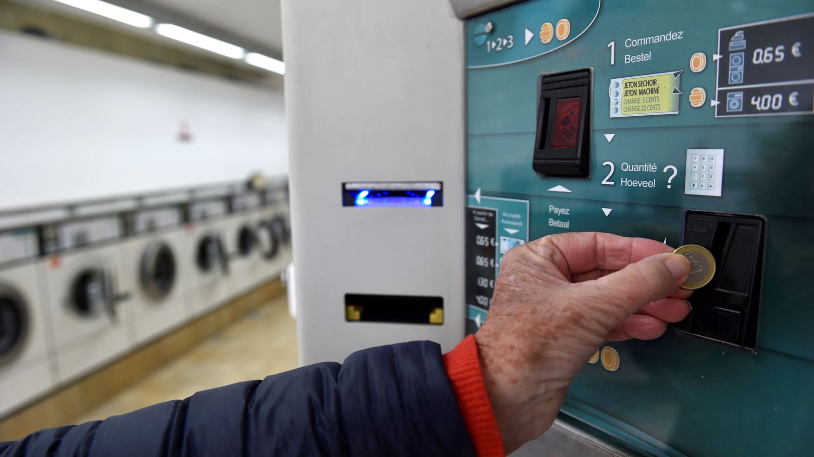 Foto: Un cliente inserta un euro en una lavandería bruselense (Eric Vidal / Reuters)
