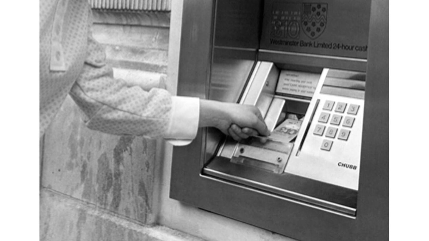 Detalle de una imagen en la que una chica extrae dinero de un cajero automático en 1969. En ella puede verse el cheque de diez libras fabricado con carbono 14. (Wikimedia)