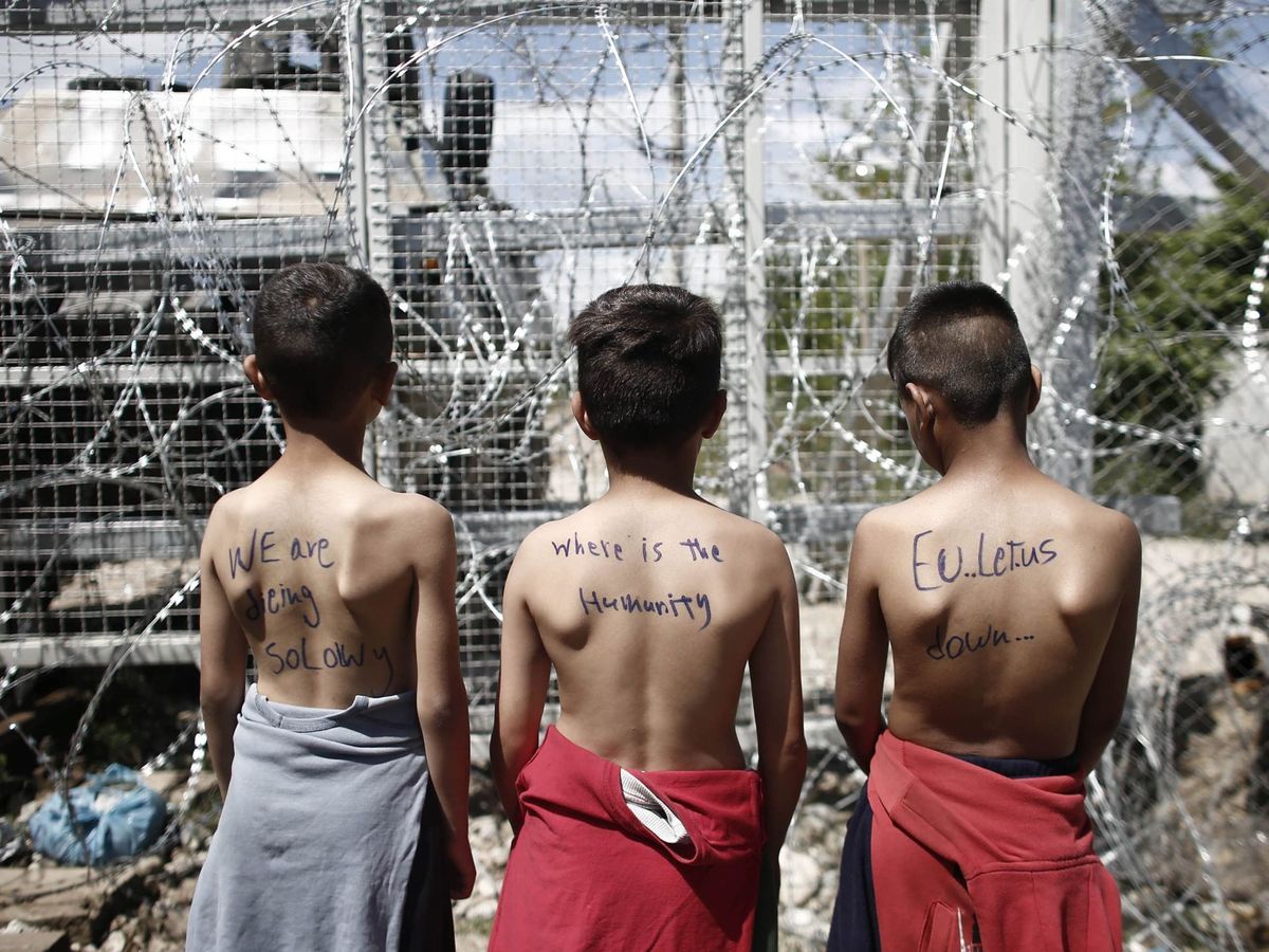 Foto: Un grupo de niños con mensajes en sus espaldas participa en una protesta en el campamento de refugiados de Idomeni (Grecia). (EFE)