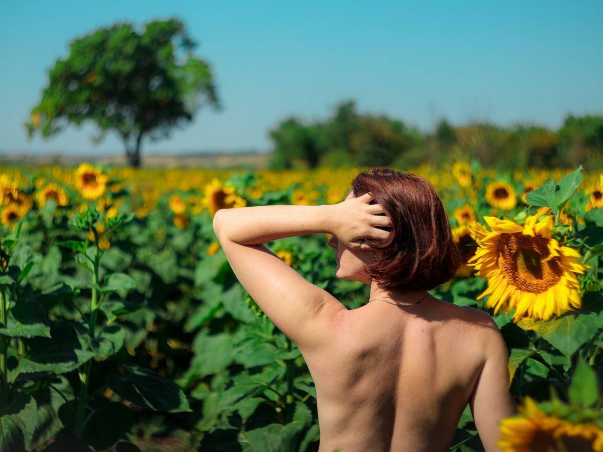 Foto: Imagen de una mujer posando desnuda en un campo de girasoles (Unsplash/Alexey Elfimov)