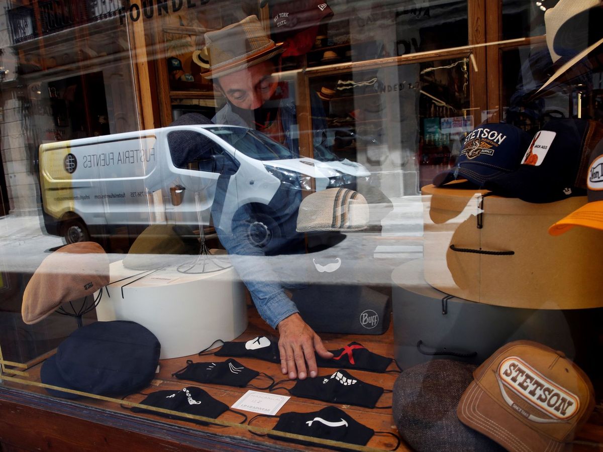 Foto: El encargado de una sombrerería coloca mascarillas en el escaparate de su tienda, este lunes, en Barcelona. (EFE)