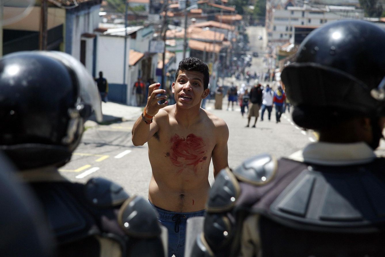 Foto: Un joven con sangre en el pecho se enfrenta a la Policía tras el asesinato de Kluiver Roa en San Cristóbal. (Reuters)