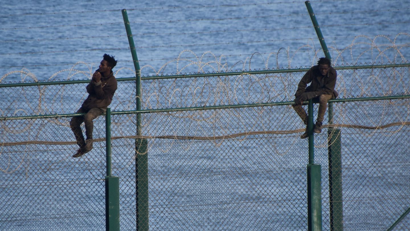 Inmigrantes subidos este viernes en la valla que separa Ceuta de Marruecos. (Reuters)