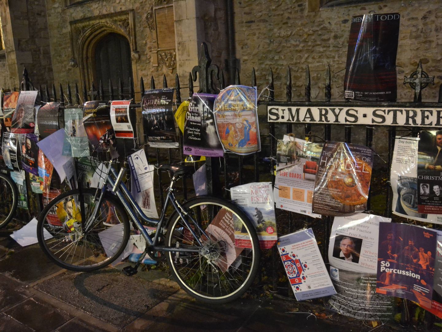 Una bicicleta apoyada en una valla con publicidad estudiantil. (E. Blanco)