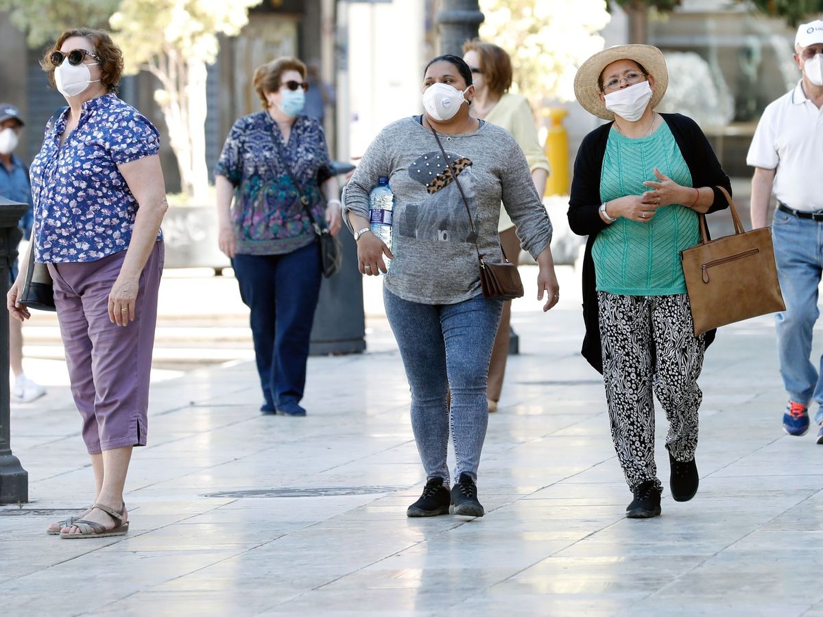 Foto: Varias personas protegidas con mascarilla en Valencia, esta mañana. (EFE)