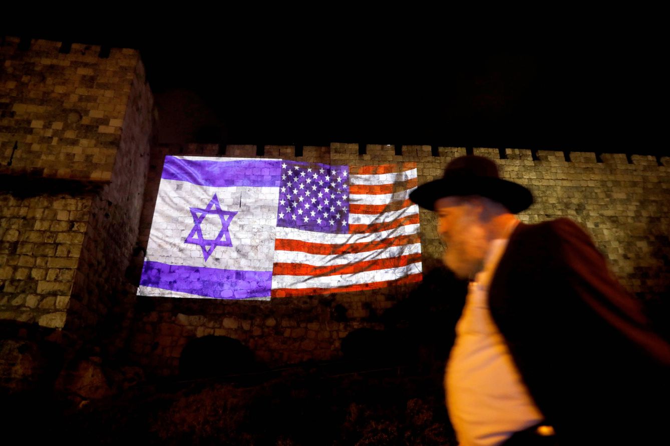 Un hombre camina ante las banderas israelí y estadounidense proyectadas sobre un muro de la Ciudad Vieja de Jerusalén. (Reuters)