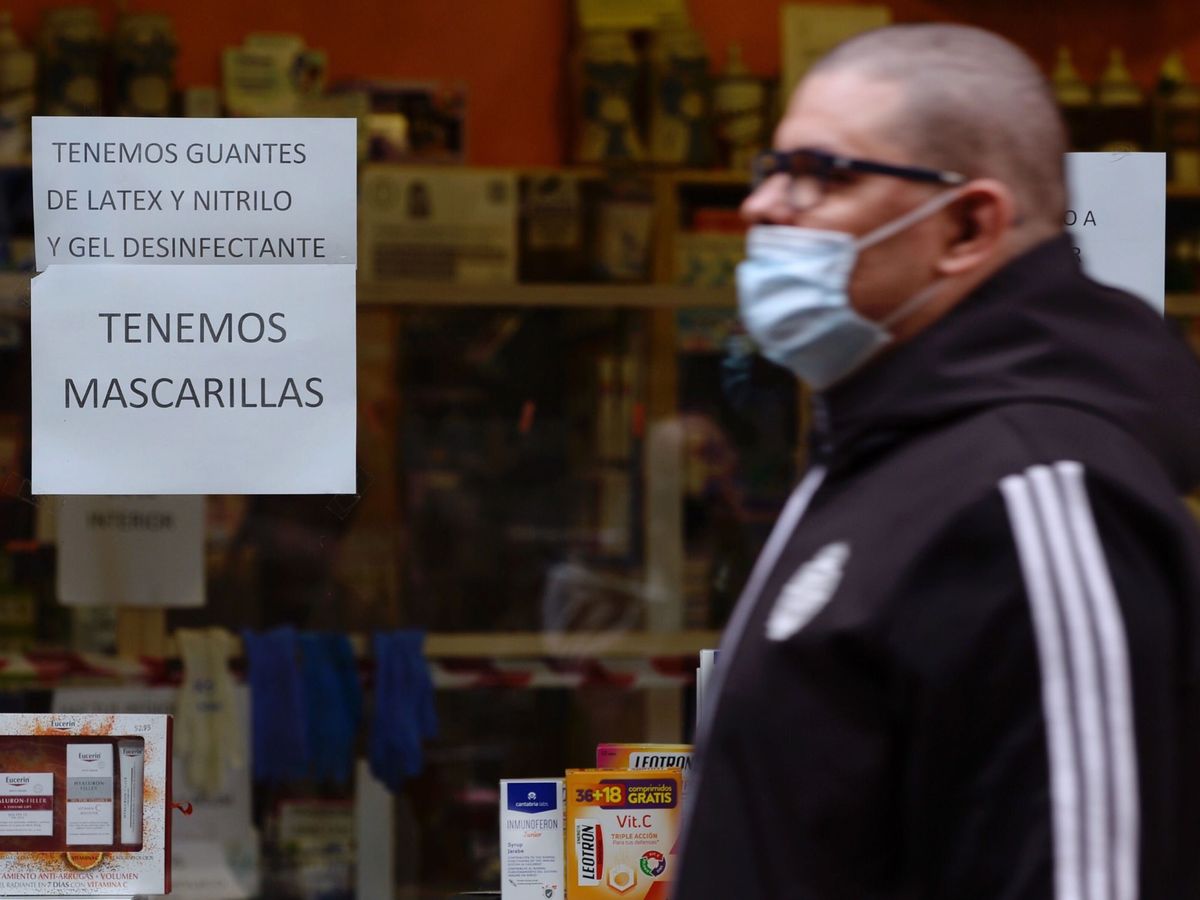 Foto: Un hombre pasa por delante de una farmacia en la que anuncian la venta de mascarillas, geles desinfectantes y guantes. (EFE)