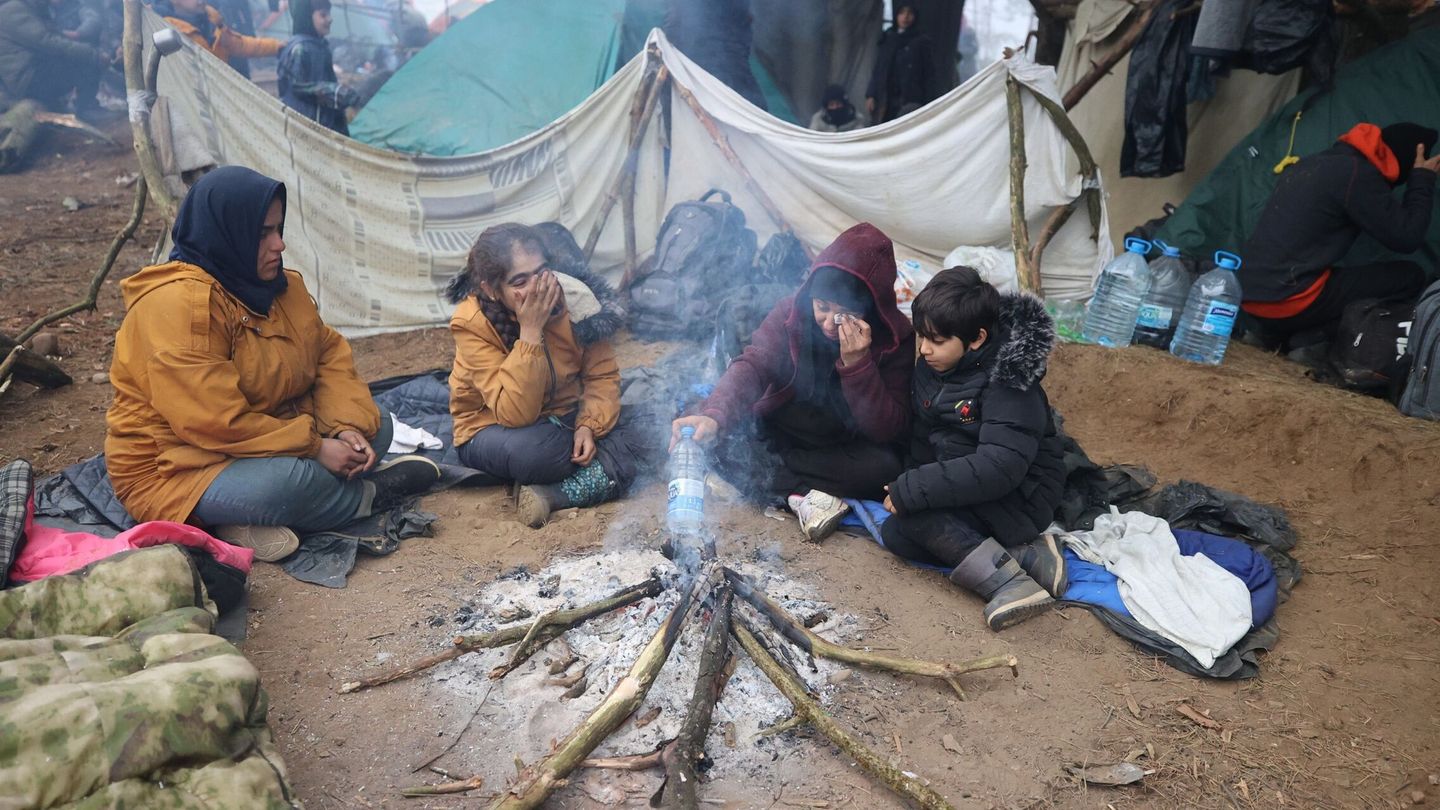 migrantes tratando de calentarse en su campamento en la frontera bielorrusa-polaca en la región de Grodno. (EFE)