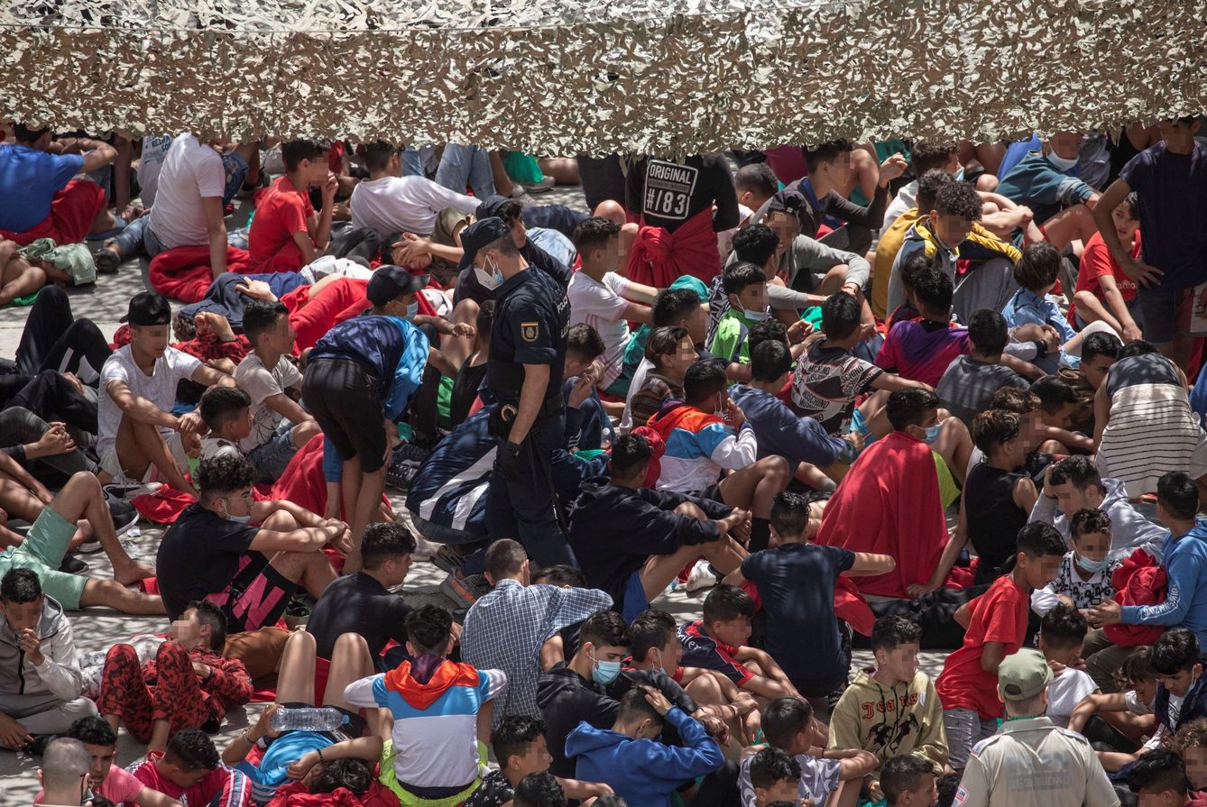 Decenas de migrantes, en la nave del polígono industrial cercano a la playa de El Tarajal. (EFE)