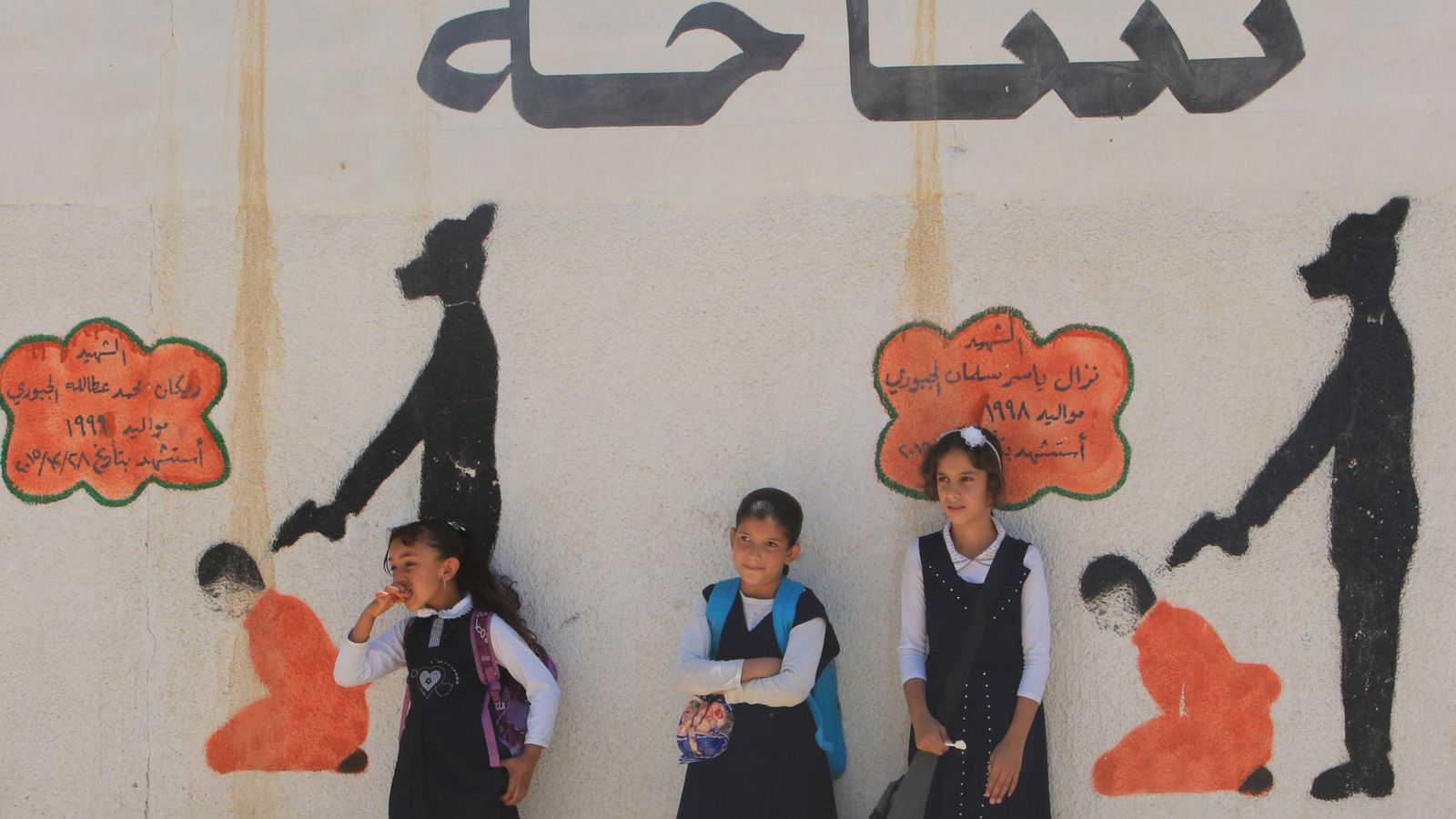 Foto: Niñas iraquíes frente a un muro escolar con dibujos de ejecuciones de prisioneros por el Estado Islámico, en Mosul, el 30 de abril de 2018. (Reuters)