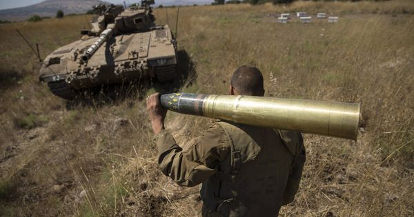Foto: Un soldado israelí carga con un proyectil cerca de Alonei Habashan, en los Altos del Golán. (Reuters)