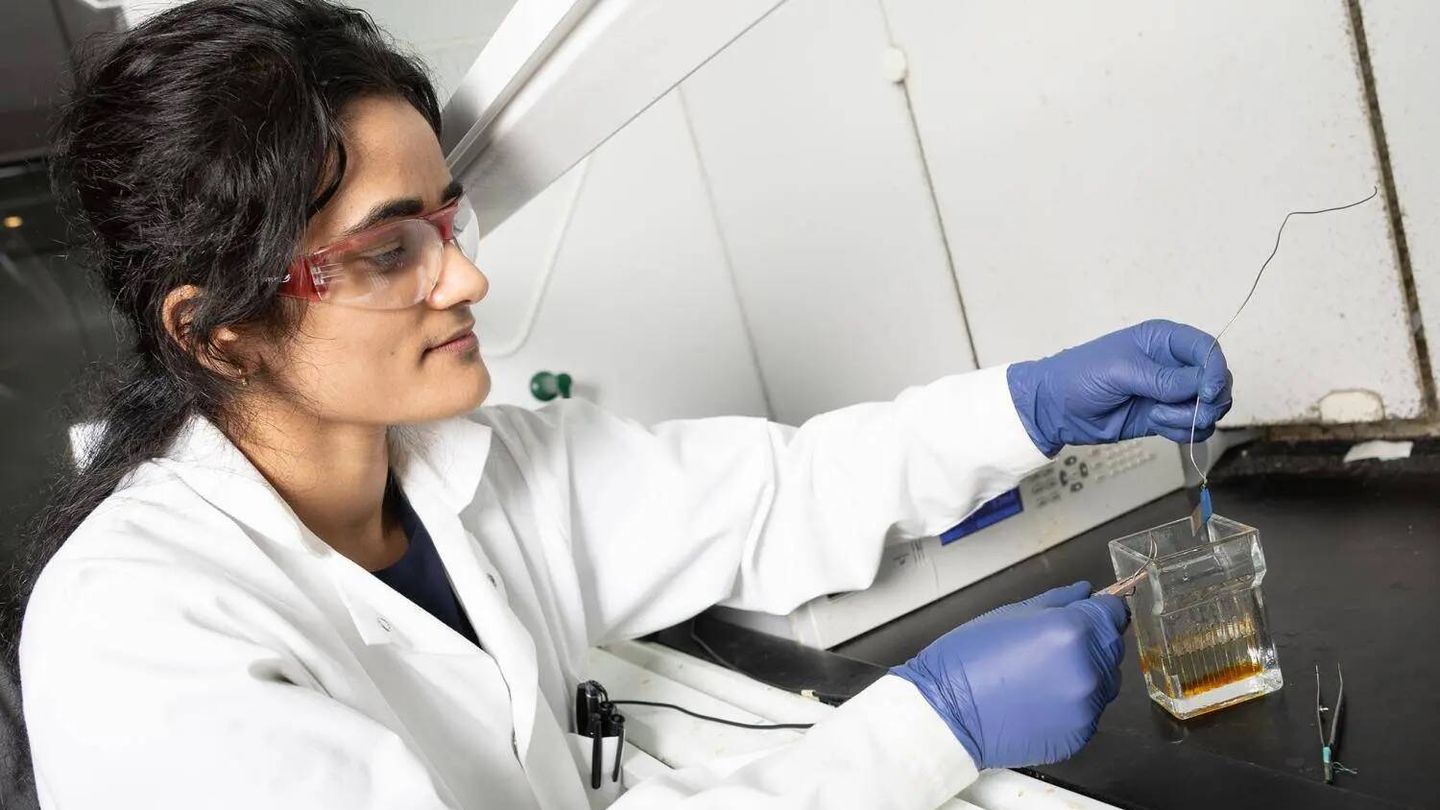 Anuja Tripathi examina una pequeña muestra de acero inoxidable después del grabado electroquímico. (Georgia Tech)