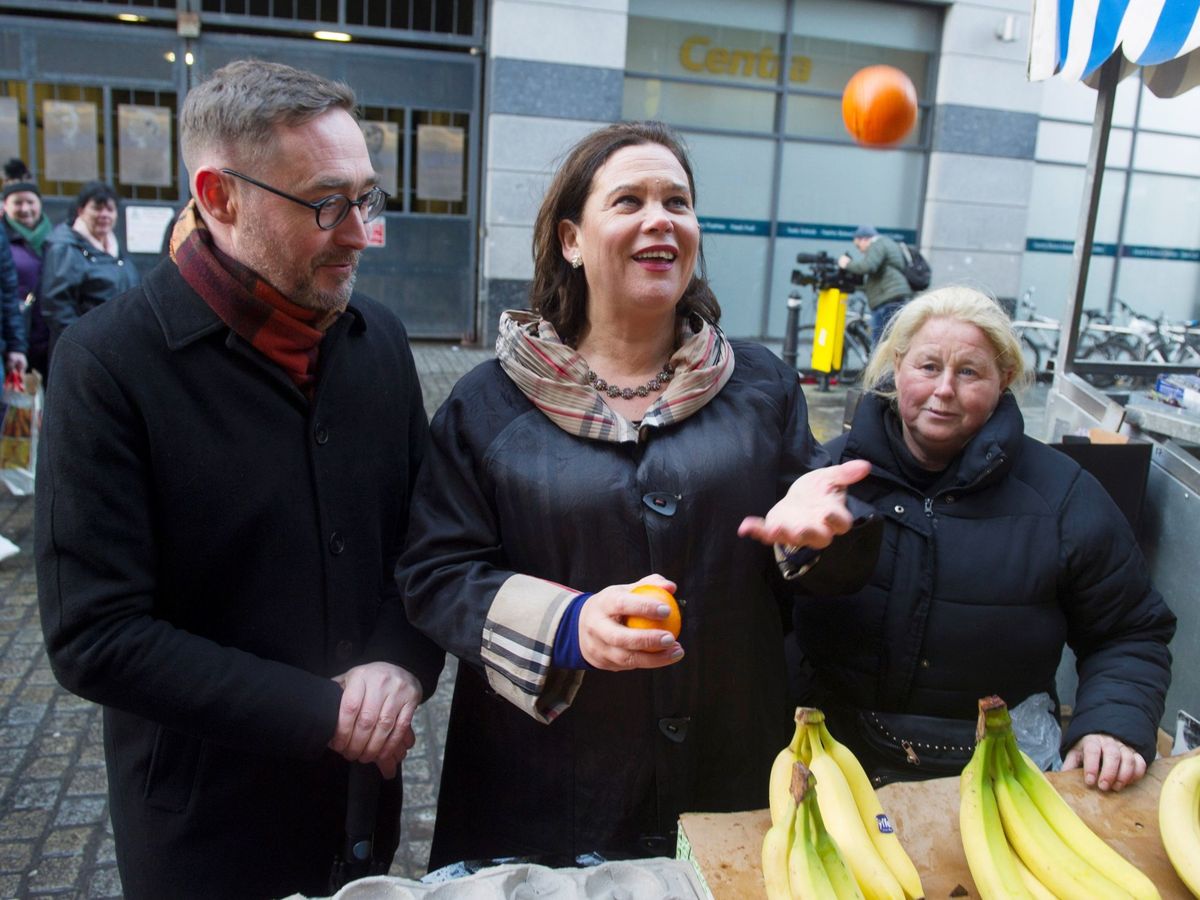 Foto: La líder del Sinn Féin, Mary Lou McDonald (C), y su compañero de partido Eoin O'Broin (i) visitan un puesto de fruta callejero en la calle Moore de Dublín (Irlanda), este lunes (EFE)