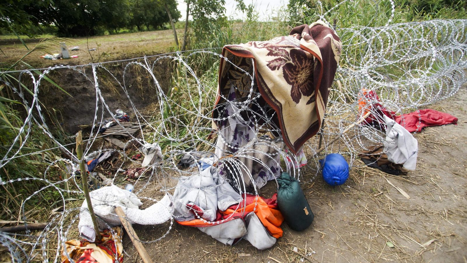 Foto: Ropas y objetos personales de los inmigrantes sobre la alambrada en Roszke, Hungría. (Efe)