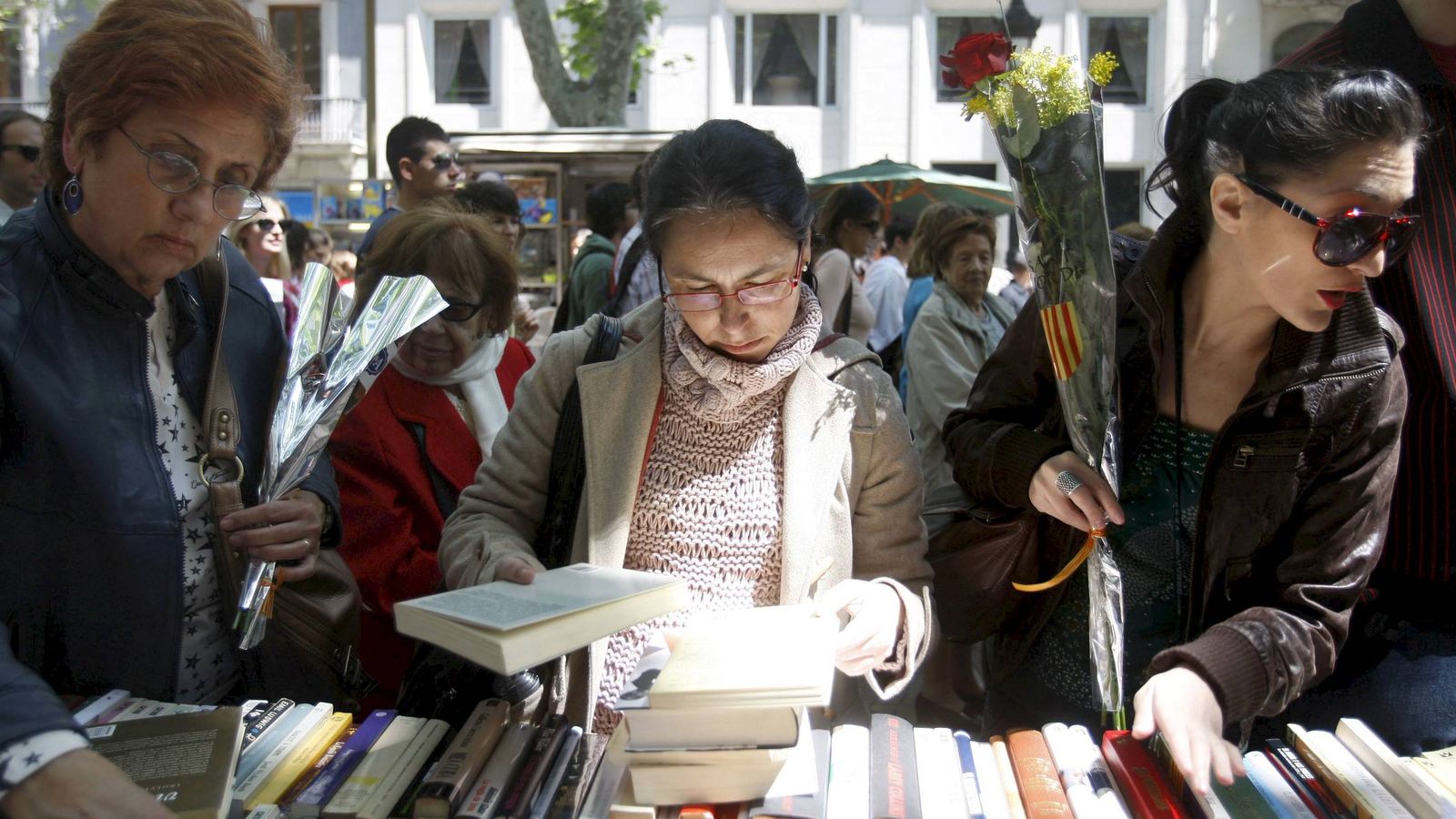 Foto: Un grupo de mujere observa libros en Barcelona durante la festividad de Sant Jordi. (EFE)