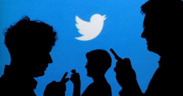 Foto: File photo: people holding mobile phones are silhouetted against a backdrop projected with the twitter logo
