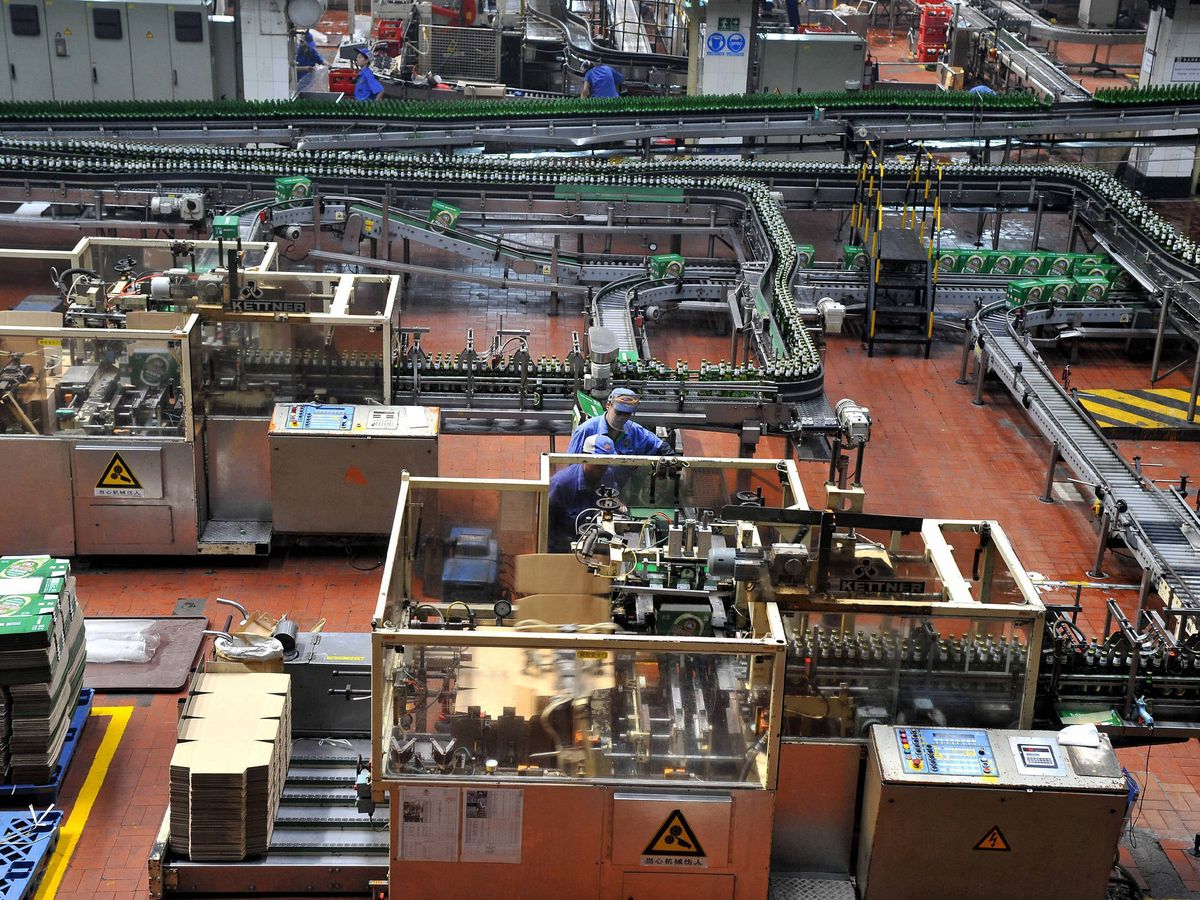 Foto: Dos operarios trabajan en una cadena de montaje de la fábrica de cerveza Tsingtao Brewery Co. (EFE)