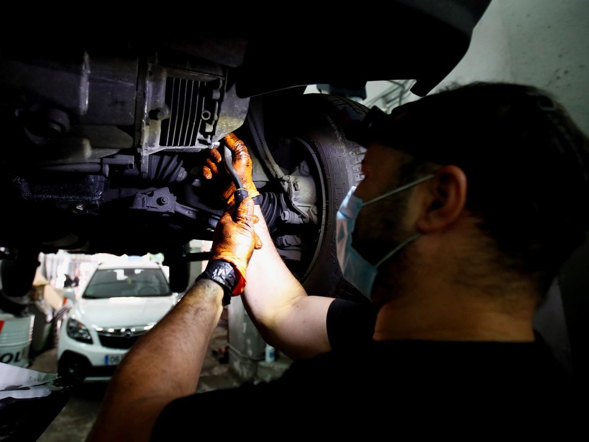 Foto: Un mecánico trabaja, con mascarilla, en un taller en Madrid. (EFE) 