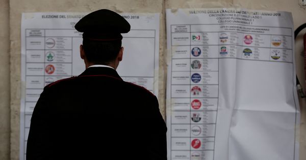 Foto: Un policía mira un cartel en un colegio electoral en Roma, ayer, 4 de marzo. (Reuters)