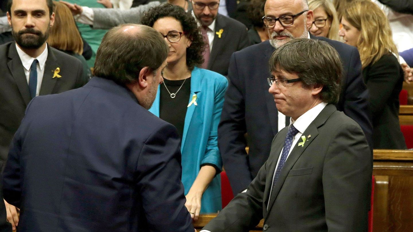 Carles Puigdemont (d) y Oriol Junqueras (i) se saludan tras aprobarse en el pleno del Parlament la declaración de independencia. (EFE)