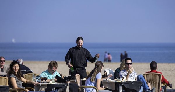 Foto: Varias personas disfrutan de las temperaturas suaves tomando un aperitivo en una terraza en la playa de La Malvarrosa de Valencia. (EFE)