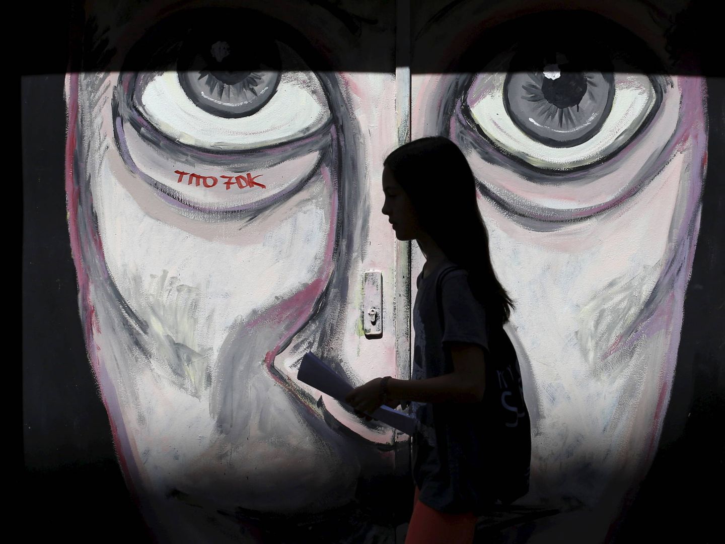 Una chica pasa por delante de un grafiti en el barrio madrileño de Malasaña. (Reuters)