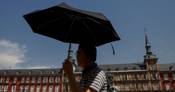 Foto: Un turista se resguarda de la ola de calor bajo un paraguas en la Plaza Mayor (Sergio Pérez / Reuters)
