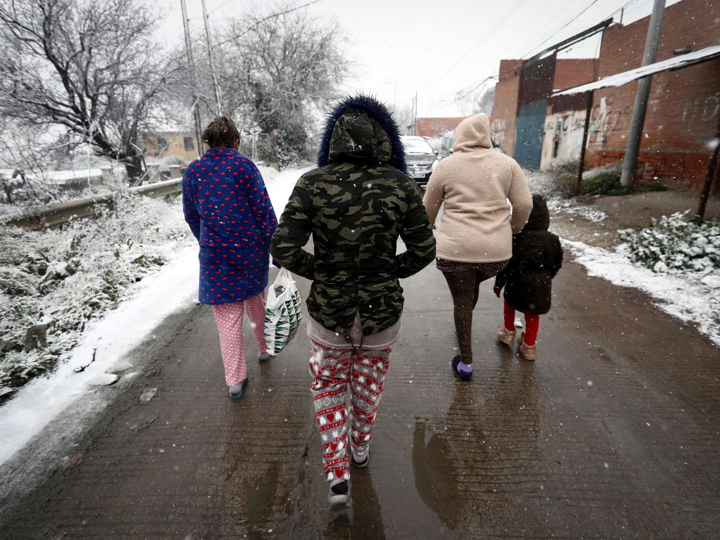Varios residentes del asentamiento de la Cañada Real caminan bajo la nieve. (EFE) 