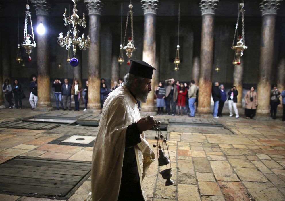 Foto: Un sacerdote ortodoxo camina ante turistas en la Basílica de la Natividad, Belén (Reuters).