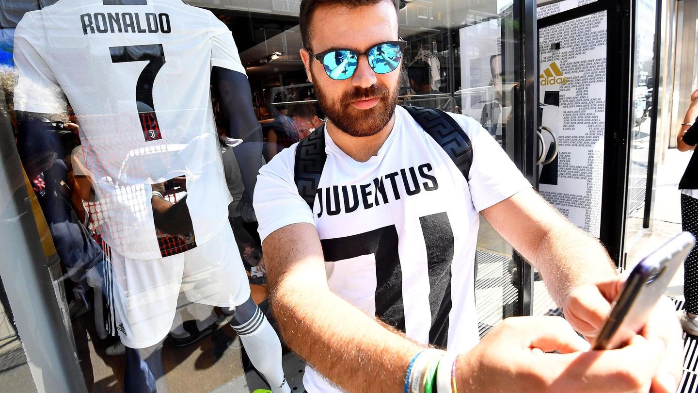 Un aficionado del Juventus posa con la nueva camiseta 'bianconera' que lucirá Cristiano Ronaldo frente a la tienda oficial del club en Milán, el 11 de julio de 2018. (EFE)