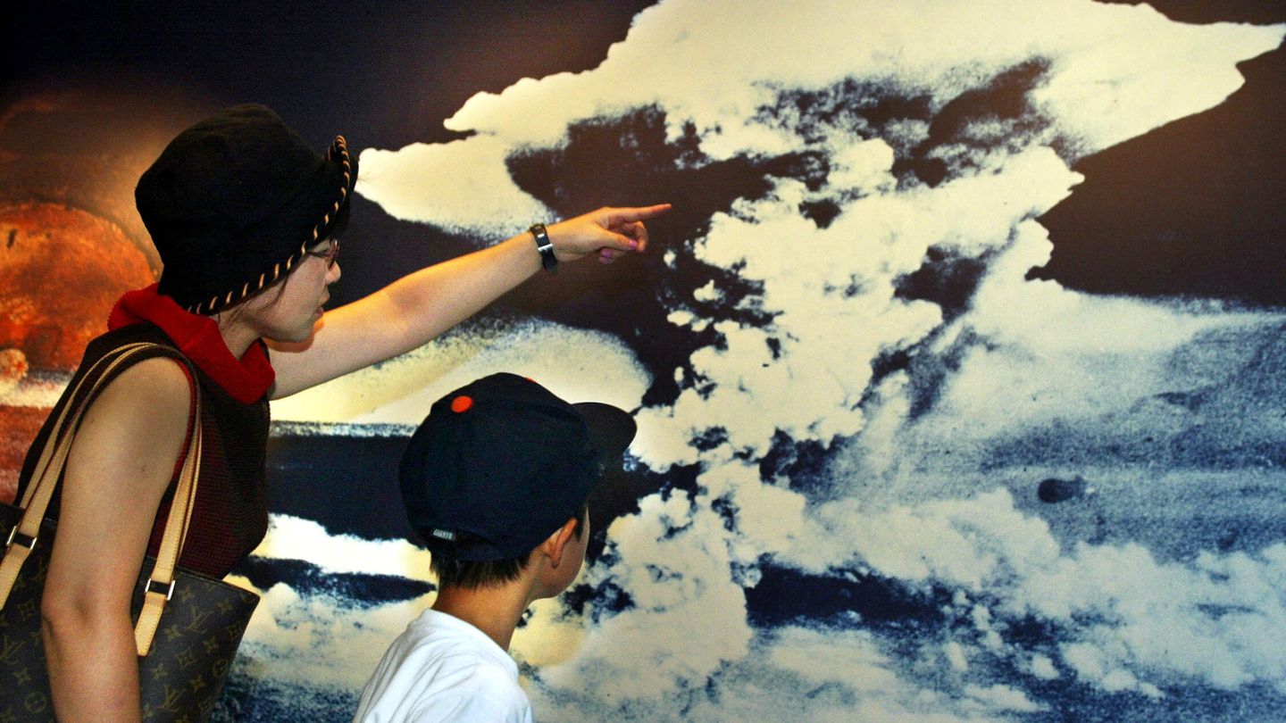 Una madre y su hijo miran una fotografia con la nube que desencadenó el lanzamiento de la bomba atómica en Hiroshima. EFE