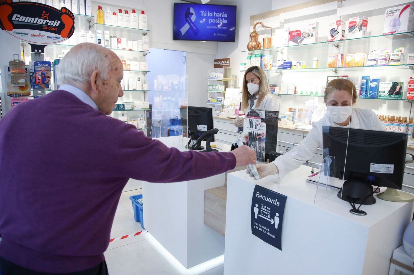 Un cliente mantiene la distancia de seguridad mientras es atendido en una farmacia del centro de Madrid (David Fernández / EFE)