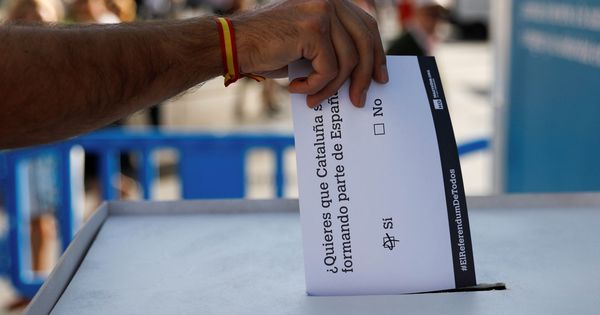 Foto: Un hombre con una pulsera de la bandera española introduce en una simulada caja de votación su supuesto voto a la consulta del próximo 1 de octubre. (Reuters)