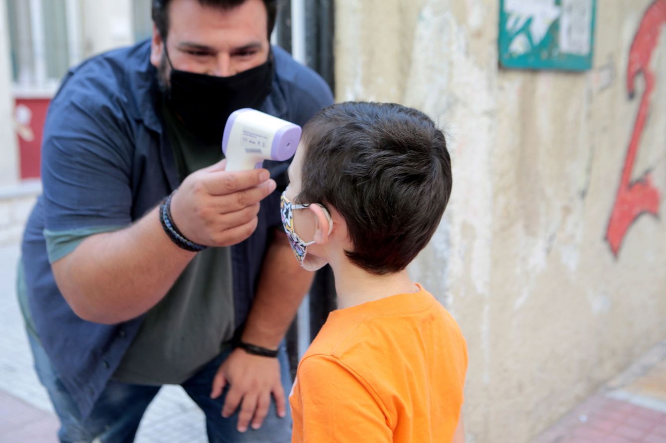 Un profesor mide la temperatura de un niño para entrar en un colegio en Atenas. (EFE)