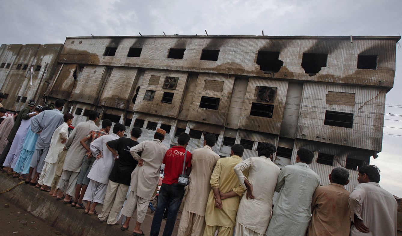 Un grupo de hombres observa la fábrica quemada, dos días después del incendio. (Reuters) 