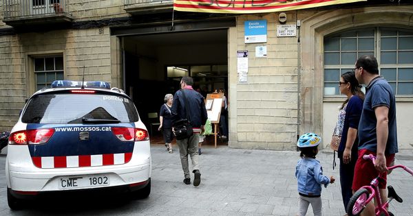 Foto: Una familia contempla la llegada de los Mossos al colegio Cervantes de Barcelona. (EFE)