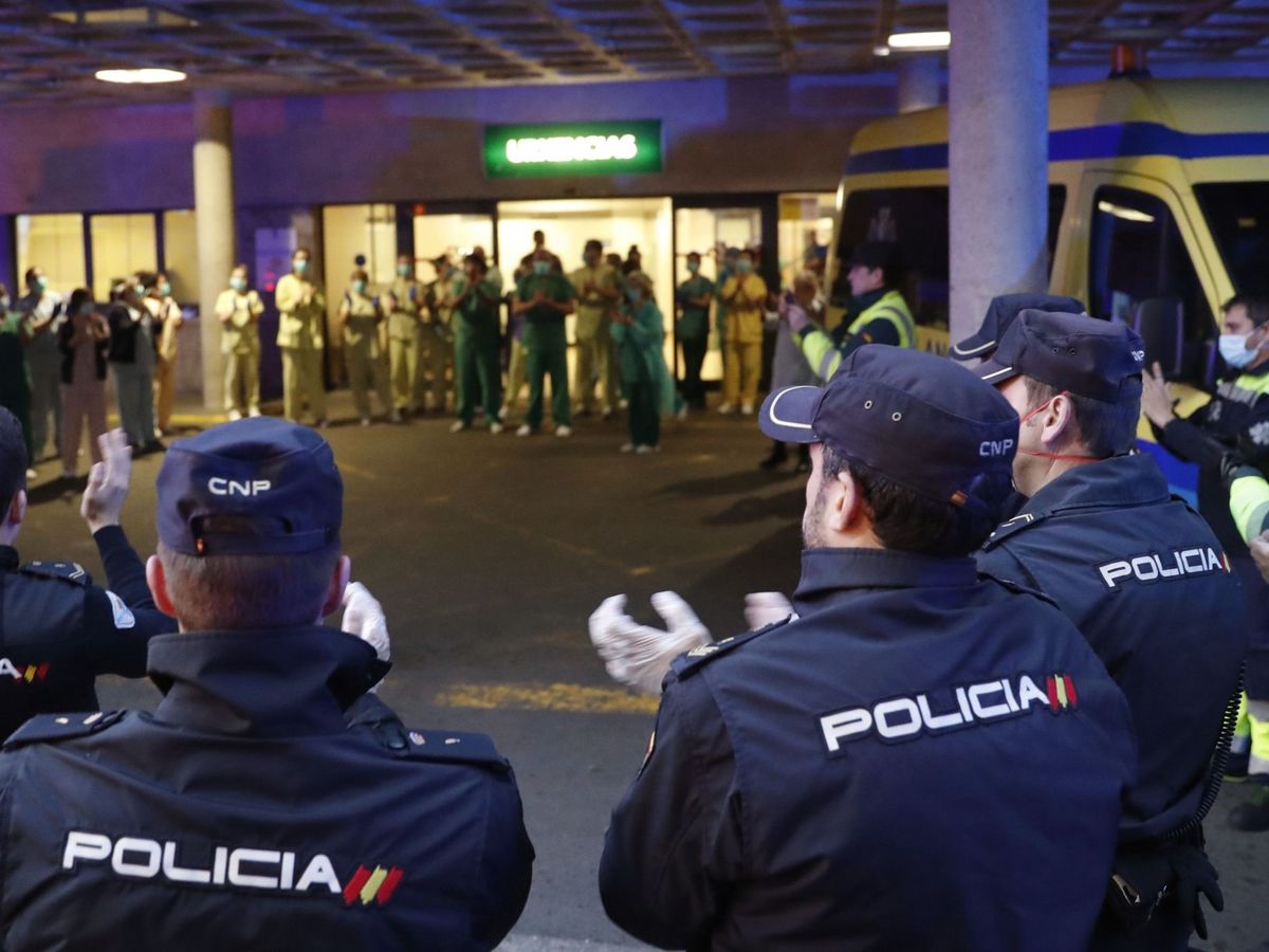 Foto: Varios policías nacionales y guardias civiles aplauden en Santiago de Compostela al personal de urgencias del hospital Clínico. (EFE)