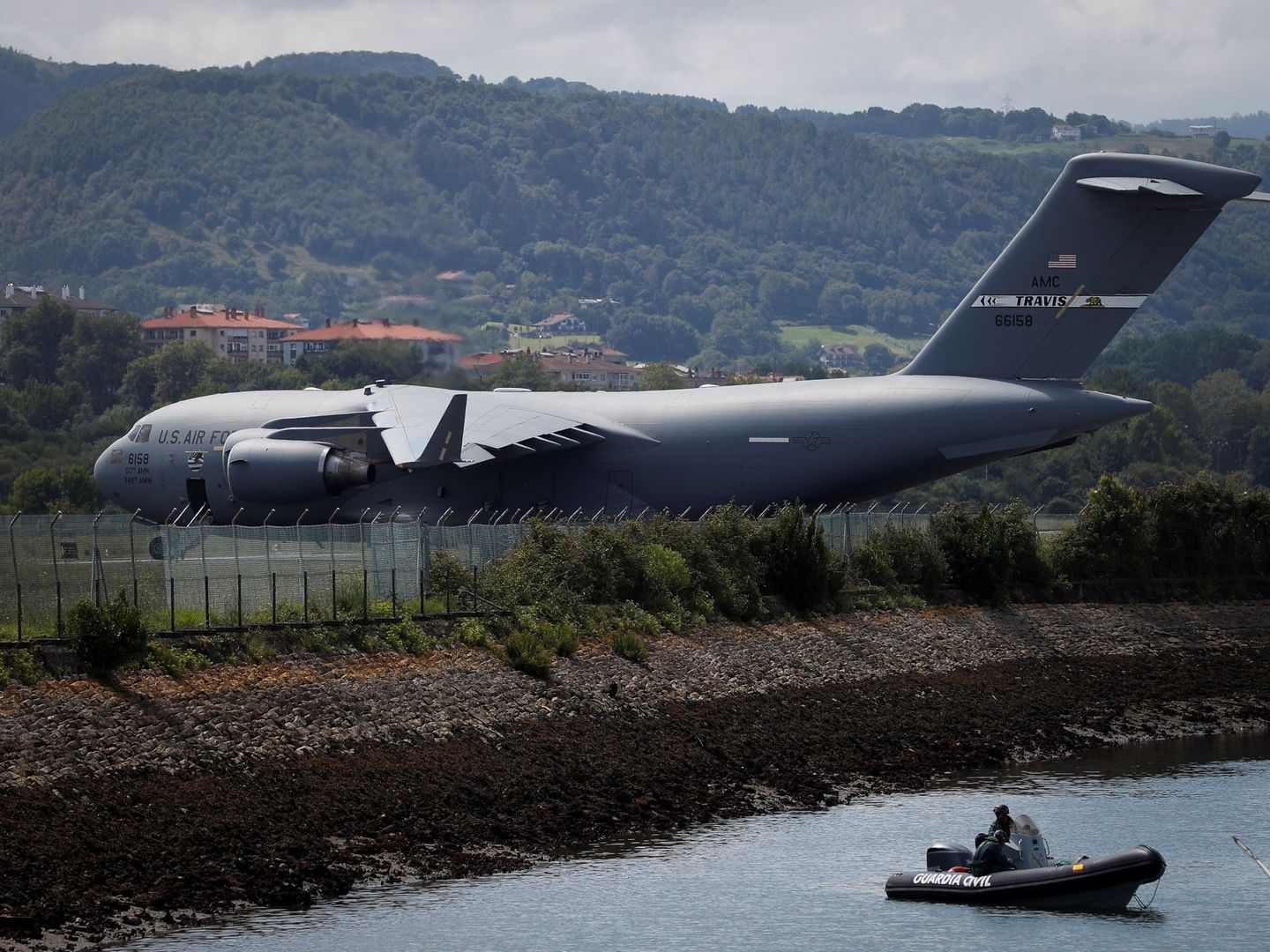 El avión militar estadounidense en el aeropuerto de Hondarribia bajo la vigilancia de dos agentes de la Guardia Civil en una lancha. (EFE)