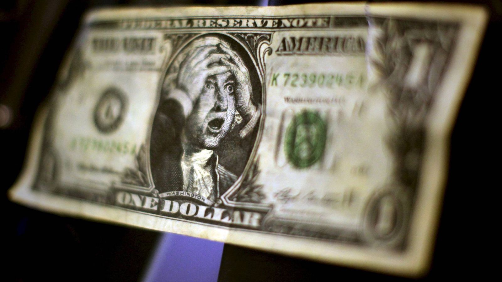 Foto: Un billete de un dólar falso con la imagen de George Washington llevándose las manos a la cabeza. (EFE)
