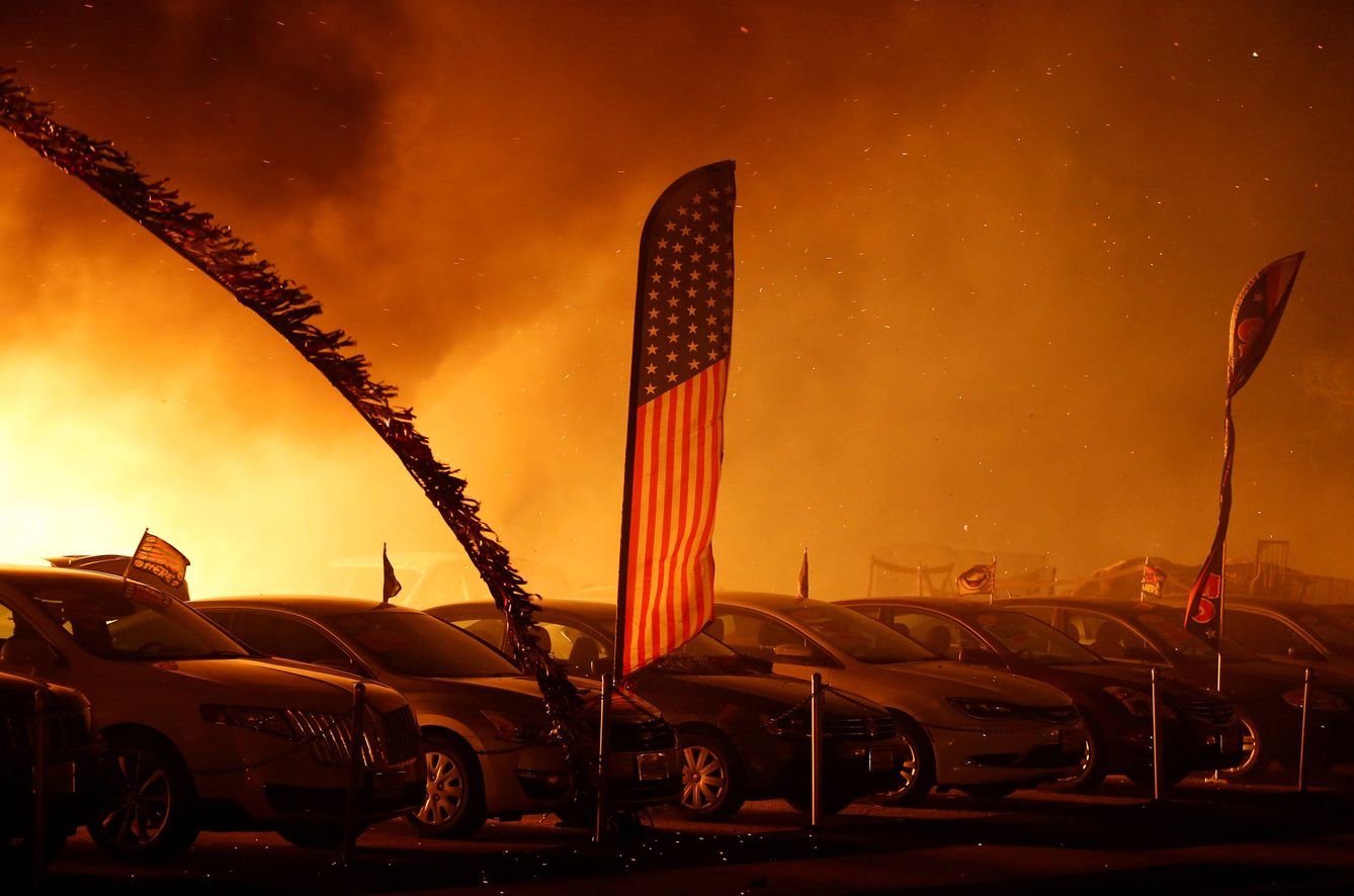 Una bandera estadounidense ondea entre las llamas en un negocio de venta de automóviles en Paradise, California, el 8 de noviembre de 2018. (Reuters)