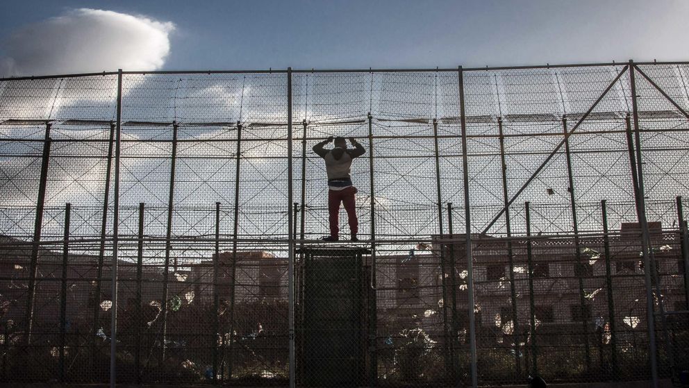 Un inmigrante africano se encarama a la valla de Melilla (Reuters).