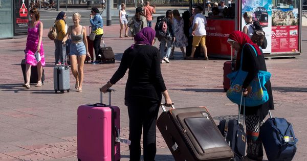 Foto: Varios turistas llevan sus maletas por la Plaza España de Barcelona. (EFE)